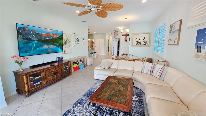 Tiled living room with ceiling fan with notable chandelier
