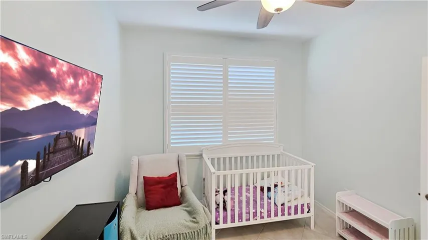 Tiled bedroom with ceiling fan and a nursery area