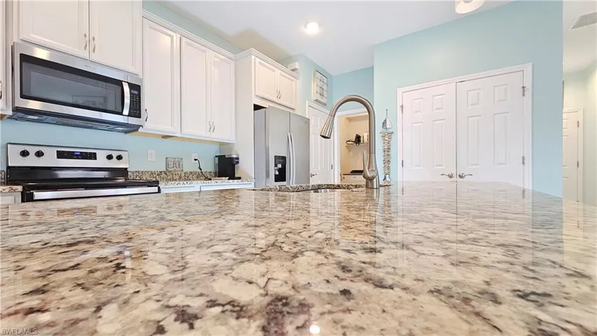 Kitchen featuring white cabinetry, light stone countertops, sink, and appliances with stainless steel finishes
