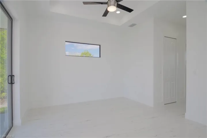 Empty room with marble finish floor, visible vents, a raised ceiling, and recessed lighting