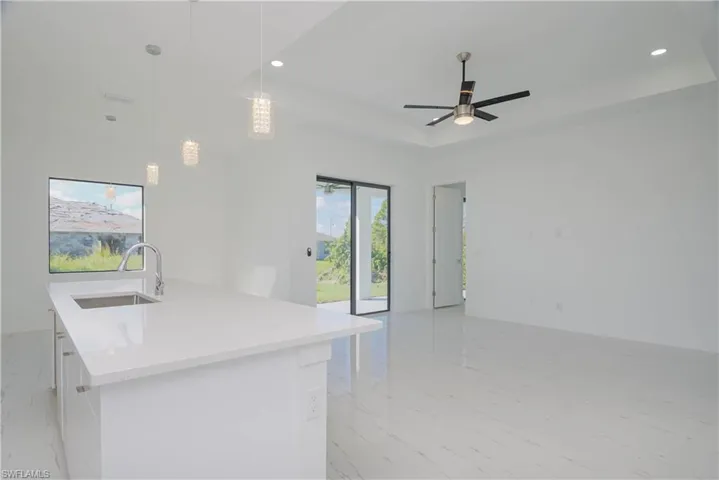 Kitchen featuring marble finish floor, a tray ceiling, open floor plan, and a sink