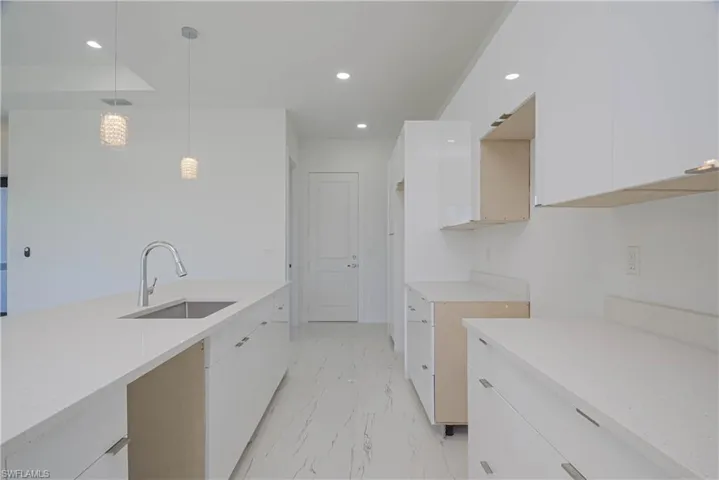 Kitchen with marble finish floor, modern cabinets, a sink, and white cabinetry