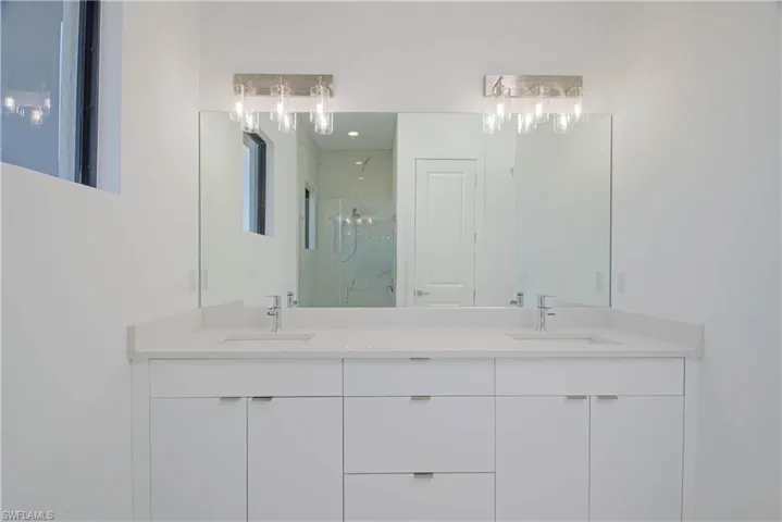 Bathroom featuring a sink, a marble finish shower, and double vanity