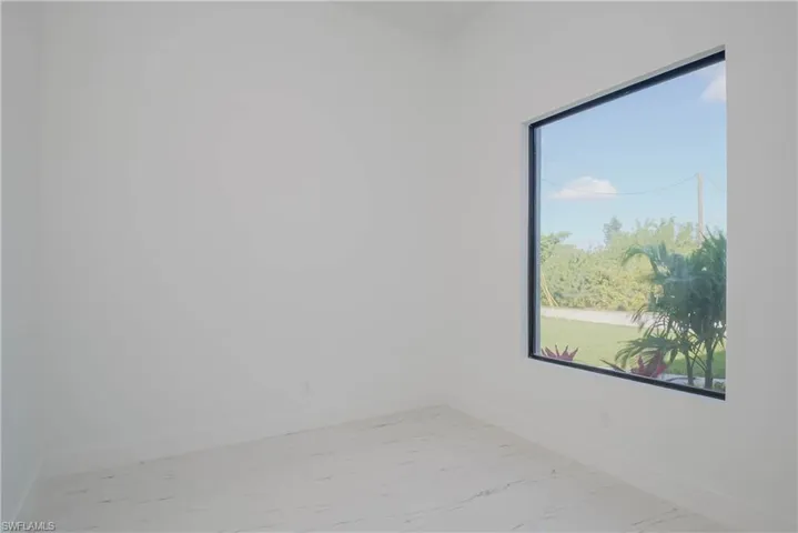 Empty room with marble finish floor, a healthy amount of sunlight, and baseboards