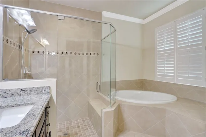 Bathroom with separate shower and tub, crown molding, and vanity