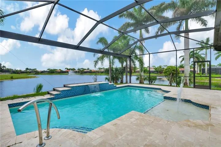 View of swimming pool with glass enclosure, pool water feature, a patio, and a water view