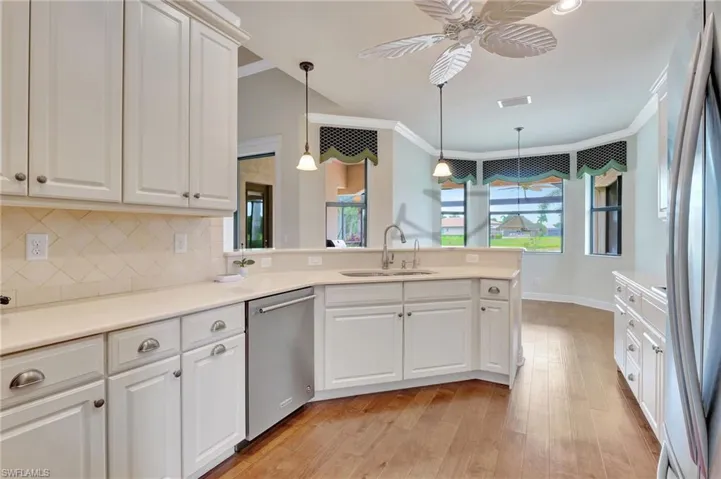 Kitchen featuring appliances with stainless steel finishes, light hardwood / wood-style floors, sink, decorative light fixtures, and crown molding