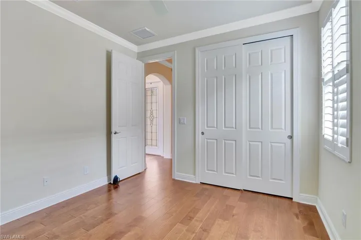Unfurnished bedroom featuring light wood-type flooring, ornamental molding, a closet, and multiple windows