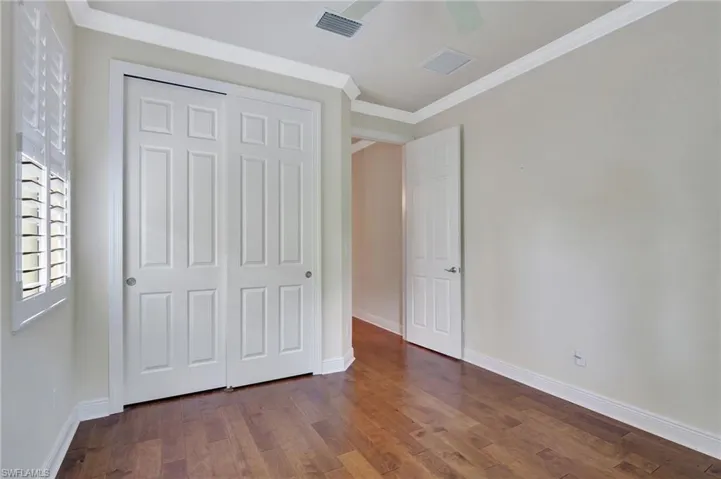 Unfurnished bedroom with ceiling fan, hardwood / wood-style flooring, crown molding, and a closet