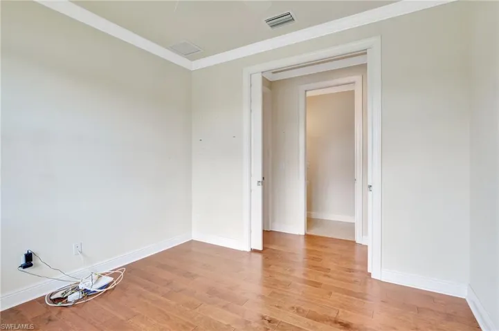 Empty room with crown molding and hardwood / wood-style floors