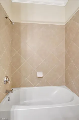 Bathroom featuring crown molding and tiled shower / bath