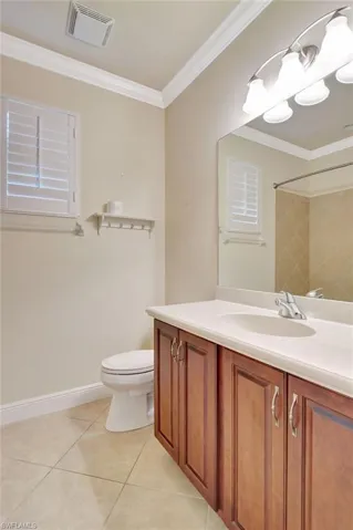 Bathroom featuring tile patterned flooring, toilet, crown molding, and vanity