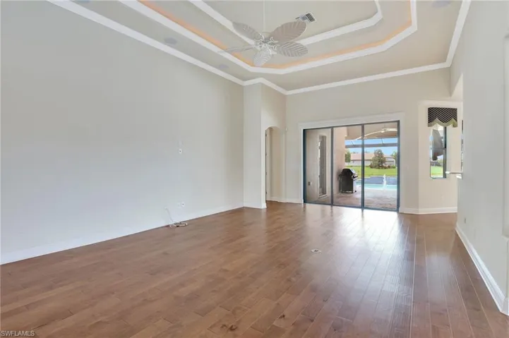 Spare room featuring ceiling fan, hardwood / wood-style flooring, crown molding, and a tray ceiling
