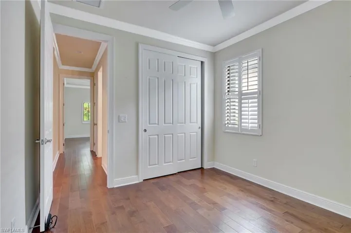 Unfurnished bedroom featuring ceiling fan, hardwood / wood-style floors, and ornamental molding