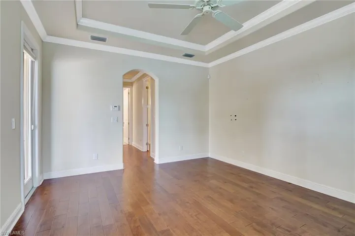 Empty room featuring hardwood / wood-style flooring, crown molding, a tray ceiling, and ceiling fan