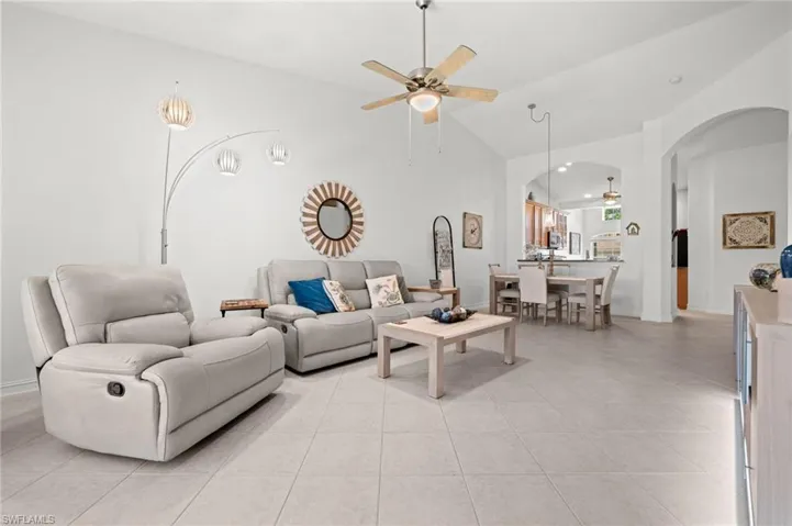 Spacious living area featuring light tile flooring, vaulted ceilings, and an arched entryway