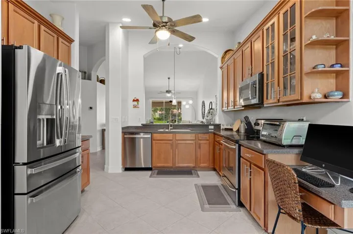 Kitchen with light wood cabinetry, stainless steel appliances, and a built-in desk area