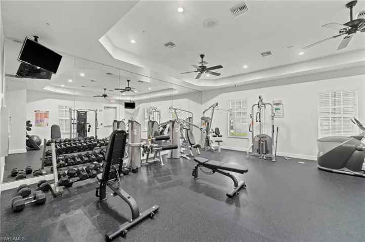 Dedicated fitness space featuring rubber flooring, mirrored wall, and recessed lighting
