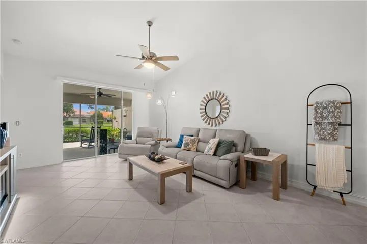Living area featuring vaulted ceilings, large format tile flooring, and a sliding glass door opening to a screened lanai