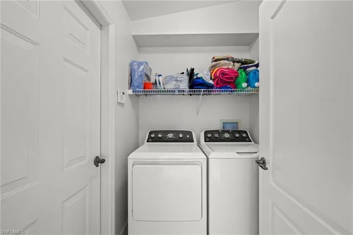 Dedicated laundry area featuring a built-in wire shelf and an upper storage shelf