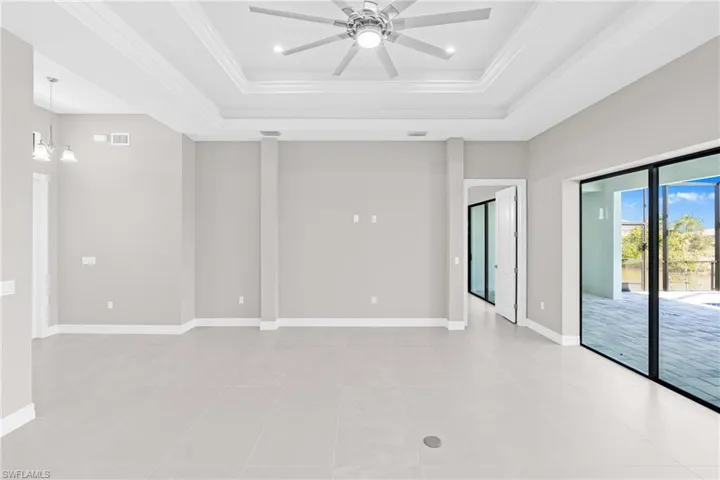 Spare room with crown molding, a tray ceiling, ceiling fan, light tile patterned floors, and a chandelier
