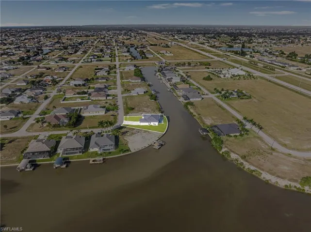 Aerial view of property and surrounding area featuring a nearby body of water and nearby suburban area