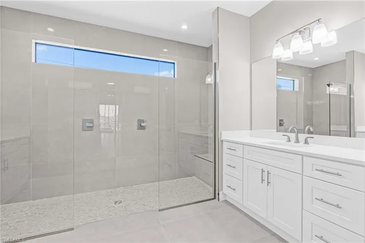 Bathroom featuring light tile patterned floors, vanity, and a walk in shower