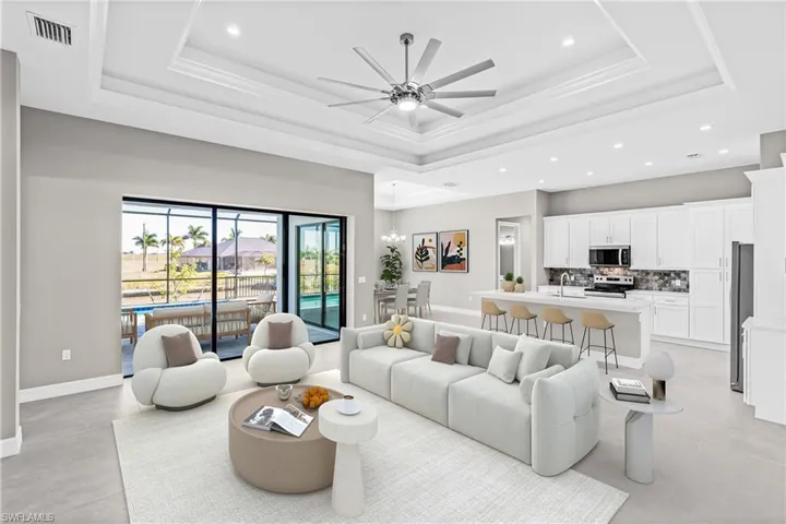 Living room with a chandelier, a tray ceiling, recessed lighting, and ceiling fan