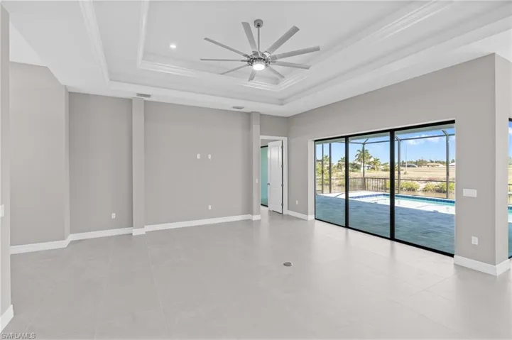 Unfurnished room featuring a raised ceiling, ceiling fan, light tile patterned flooring, recessed lighting, and crown molding