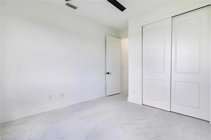 Unfurnished bedroom with light marble finish floors, a ceiling fan, and a closet
