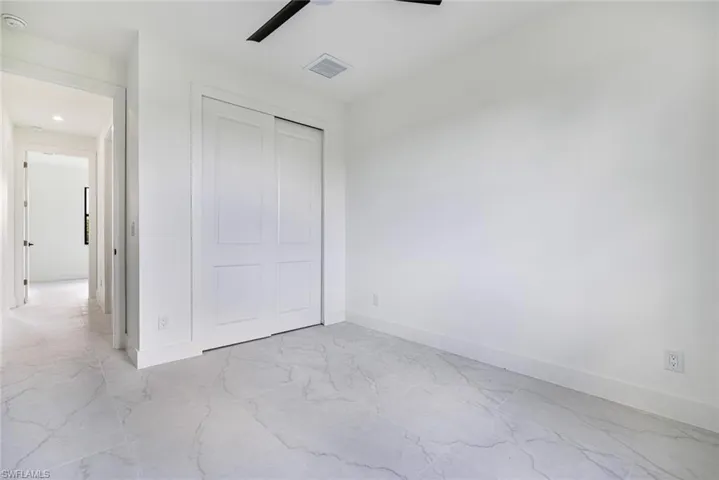Unfurnished bedroom with a ceiling fan, a closet, and light marble finish floors