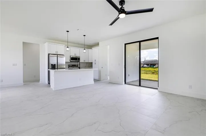 Kitchen featuring open floor plan, a kitchen island with sink, white cabinetry, and stainless steel appliances