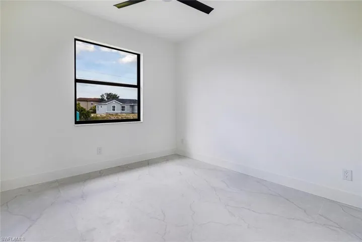 Empty room featuring ceiling fan and light marble finish floors