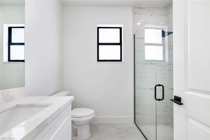 Full bath featuring a marble finish shower, vanity, and light marble finish flooring