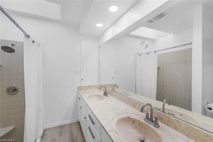 Bathroom with a shower with shower curtain, hardwood / wood-style floors, a skylight, and vanity