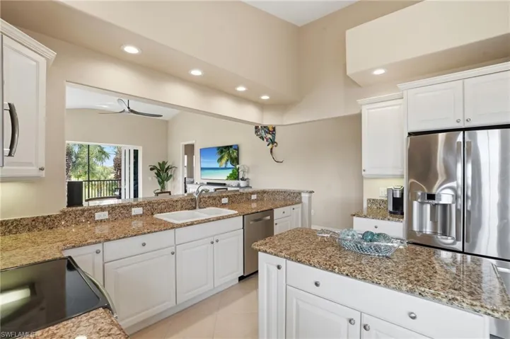 Kitchen with white cabinets, recessed lighting, stainless steel appliances, light stone countertops, and a ceiling fan