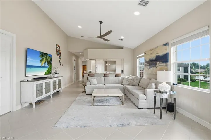 Living area with vaulted ceiling, recessed lighting, a ceiling fan, and light tile patterned flooring