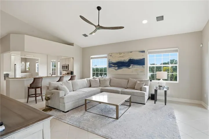 Living room with a ceiling fan, light tile patterned flooring, lofted ceiling, and recessed lighting