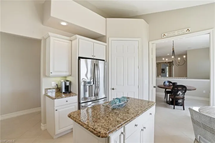 Kitchen with stainless steel refrigerator with ice dispenser, white cabinets, dark stone countertops, a chandelier, and a center island