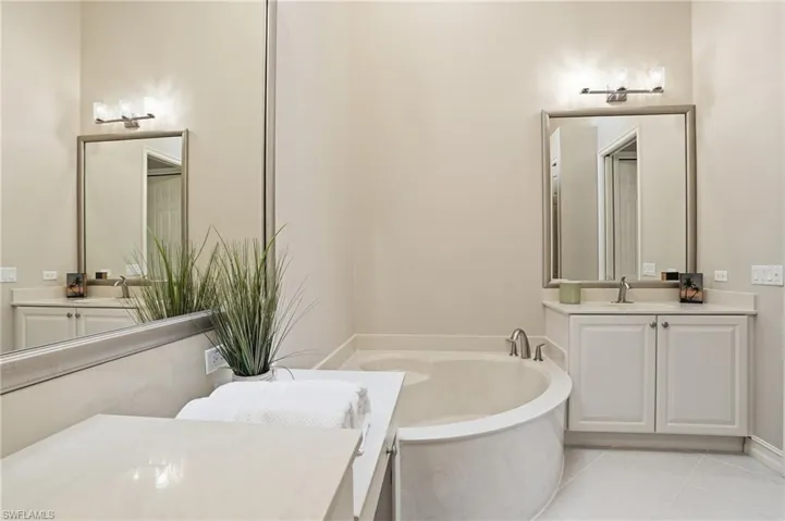 Bathroom with two vanities, a garden tub, and light tile patterned floors