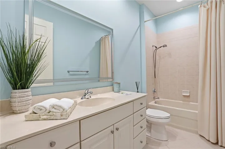 Full bathroom featuring vanity, shower / bathtub combination with curtain, and light tile patterned flooring