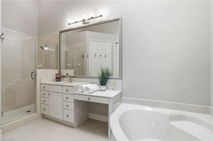 Bathroom with vanity, a shower stall, light tile patterned floors, and a garden tub