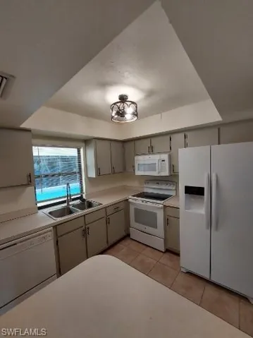Kitchen featuring white appliances, light countertops, light tile patterned flooring, and gray cabinetry