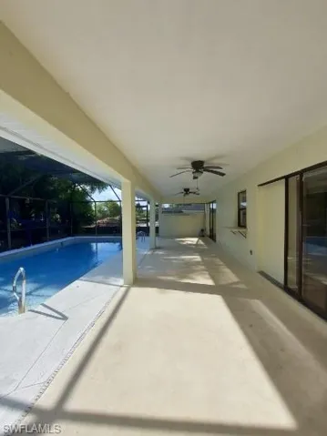 Swimming pool featuring a patio, a ceiling fan, glass enclosure, and a sunroom