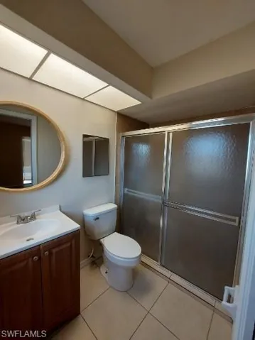 Bathroom with a shower stall, light tile patterned floors, and vanity