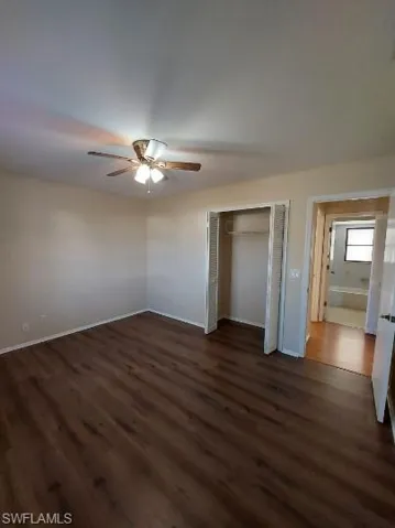 Unfurnished bedroom with dark wood-type flooring, a closet, and ceiling fan