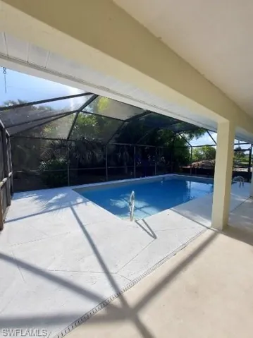 Swimming pool with a sunroom, a patio, and glass enclosure