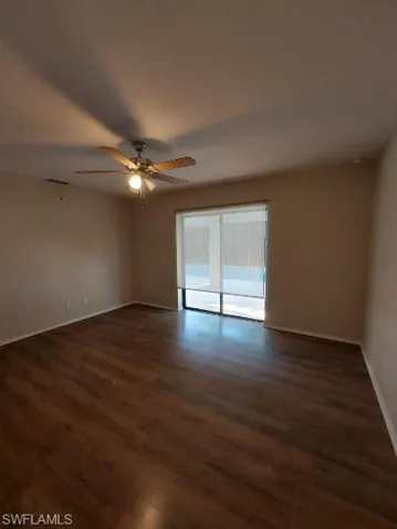 Unfurnished room featuring dark wood-type flooring and a ceiling fan