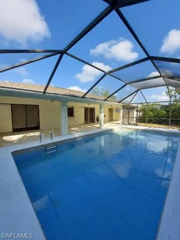 Swimming pool featuring a sunroom, a lanai, and a patio