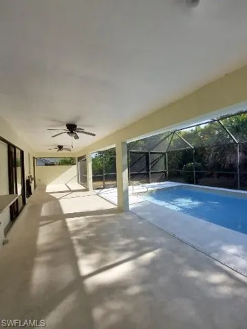 Outdoor pool with ceiling fan, a patio, a sunroom, and glass enclosure